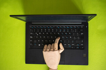 Wooden mannequin hand typing on laptop – AI and technology concept