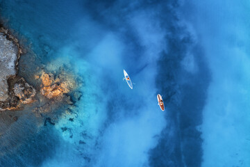 Aerial view of people on floating kayaks on blue sea, rocky coast, trees at sunrise in summer. Blue lagoon, Oludeniz, Turkey. Tropical landscape. Sup boards on clear water. Top view of canoe. Tourism - Powered by Adobe