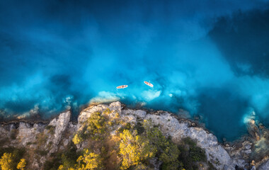 Aerial view of people on floating kayaks on blue sea, rocky coast, trees at sunset in summer. Blue lagoon, Oludeniz, Turkey. Tropical landscape. Sup boards on clear water. Top view of canoe. Tourism