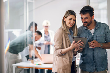 Two young businesspeople using a digital tablet while in an office.