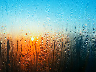Fogged glass from dampness. Behind wet glass, you can see morning dawn.