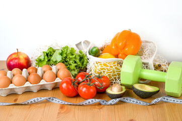 Vegetables,fruit and eggs near dumbbells and measuring tape. Sport and diet cocnept. HEalthy lifestyle