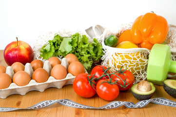 Vegetables anf fruit near dumbbells and measuring tape. Sport and diet cocnept. HEalthy eating habits