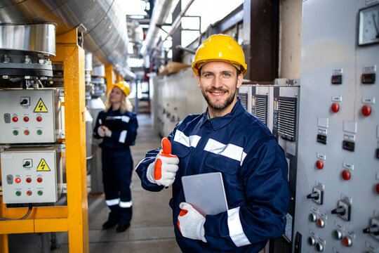 Portrait of factory worker holding thumbs up in petrochemical industrial refinery.