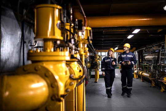 Industrial workers controlling production of natural gas and distribution in refinery.
