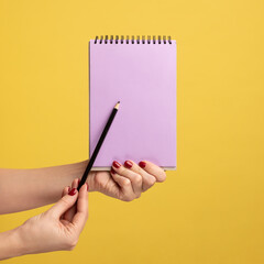 Profile side view closeup of woman hand holding purple notepad in hand and showing empty paper with...
