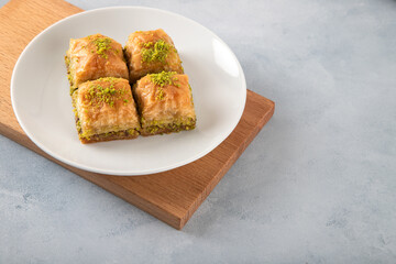 Pistachio baklava in a white plate on wooden background

