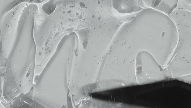 Serum gel with peptides texture spreading with spatula footage. Liquid cosmetic skincare toner beauty product with ceramide and collagen. Hyaluronic acid cleanser abstract background video 4k
