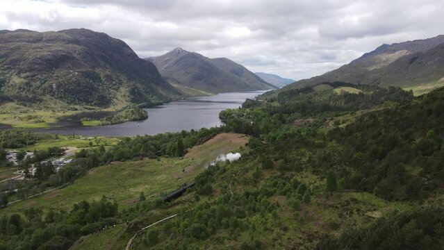 Wide aerial of Hogwart's Express (Harry Potter) steam train travelling over the Glen Finnan Viaduct in the Scottish Highlands with Loch Shiel in the background