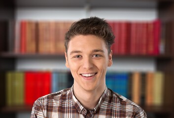 Obraz premium Happy schoolboy guy posing in campus library on bookshelves background.