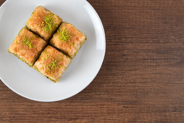Pistachio baklava in a white plate on wooden background	