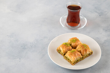 Pistachio baklava on a white plate with Turkish tea	