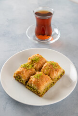Pistachio baklava on a white plate with Turkish tea	