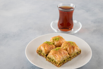 Pistachio baklava on a white plate with Turkish tea	