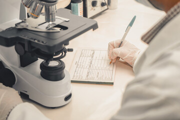 Latin Clinical analyst from Nicaragua writing down the results of a laboratory sample examined...