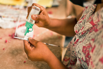 Unrecognizable Nicaraguan woman putting glue on paper to make crafts and recycle waste - obrazy, fototapety, plakaty
