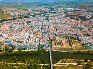 Aerial panoramic view of modern Merida cityscape on banks of Guadiana River with ancient pedestrian Roman Bridge, Spain