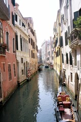 Góndola estacionada en canal de agua que une con un puente grupo de casas antiguas adosadas en Venecia