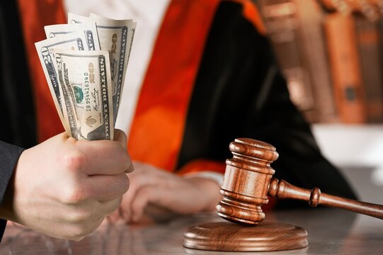 Law, auctioning, corruption, bankruptcy, judge gavel standing on sound block and bundle of dollars