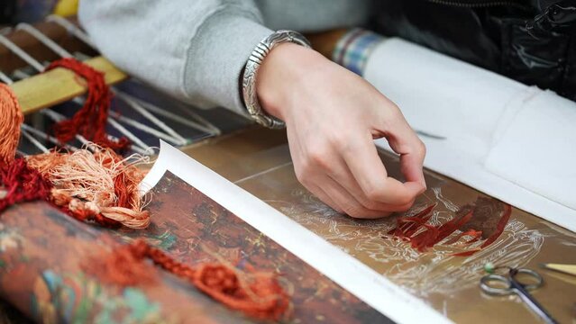 chinese female intangible culture heritage artist stitching on cloth
