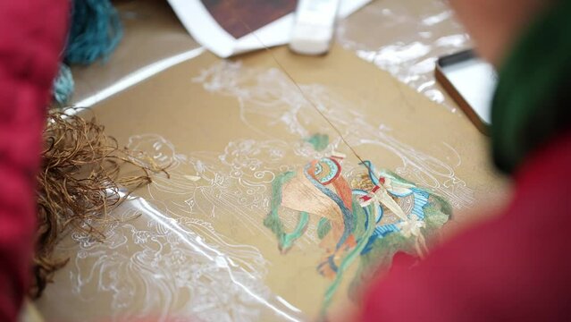 chinese female intangible culture heritage artist stitching on cloth
