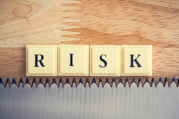 Word RISK with saw blade on wooden table background. Risk management, risk assessment in business finacial and investment or insurance concept.