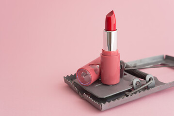 Red lipstick in rat trap on pink background copy space. Online internet romance scam or swindler in...