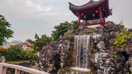 A pavilion with a waterfall in a garden in Okinawa, Japan