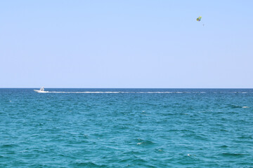 paraglider being pulled by boat in the open ocean, traveling left