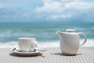 Transparent cup with pot on wooden table in front of sea