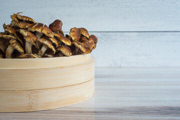 Side of cinnamon cap mushroom in bamboo bowl on dark wooden and shiplap surface