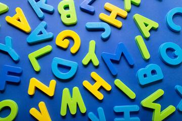 Scattered letters on blue background. Several capital letters in disorder on blue background. Education concept