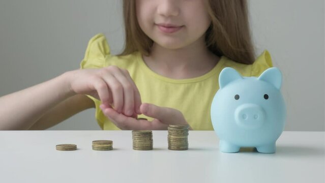 Provident economical little girl child girl stacks coins near piggy bank saving for future needs. Savings, budget planning. Happy smart small 9s teen kid make donation contribution in piggybank