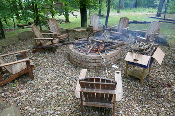 Brick fire pit with smoldering fire surrounded by adirondack chairs