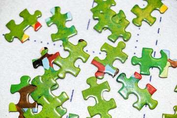 Pile of jigsaw puzzle pieces on white matt background close up
