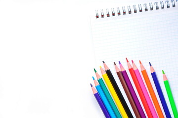 blank page of a notebook for notes with colorful pencils and copy space on white background