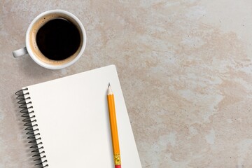 A notebook with pencil  and coffee cup on desk texture.