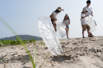 Asian Family volunteer picking up a plastic bottle on a beach with a sea to protect an environment