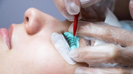 Young woman undergoing eyelash tinting and lamination procedure.