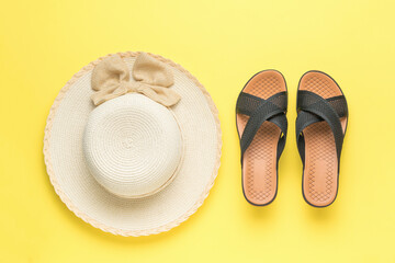 A large women's hat and black summer sandals on a yellow background. Minimal summer concept.