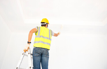 A view of the painter behind the wall painter with a paint roller and split bucket on a large empty space with a wooden staircase.