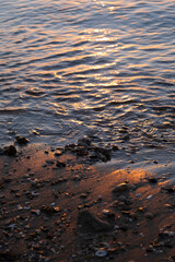 Red Sea close up view. Sea wave nailed stones to the sandy beach. Vertical photo. Reflection of the sunset in the waves.
