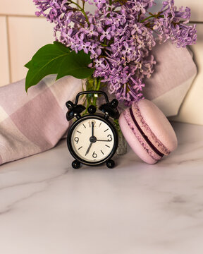 Macaroons and an alarm clock with a branch of flowers in lilac tones. Syrínga