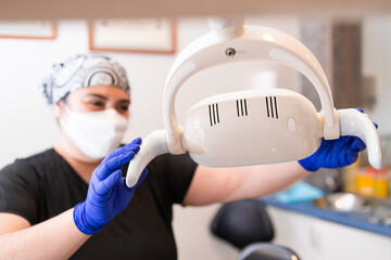 Female dentist preparing dental chair light. Selective focus