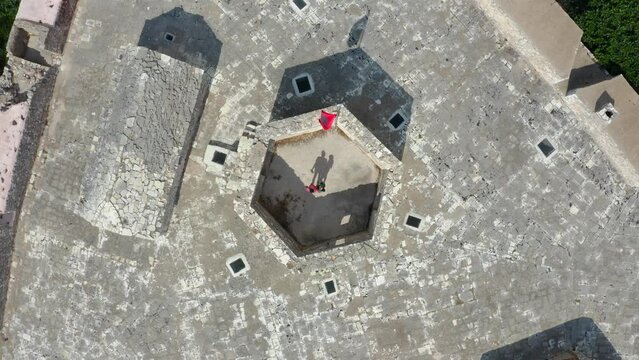Rising aerial top down of young couple standing on the top of Ali pasha fortress Venetian Triangular Castle Porto Palermo.