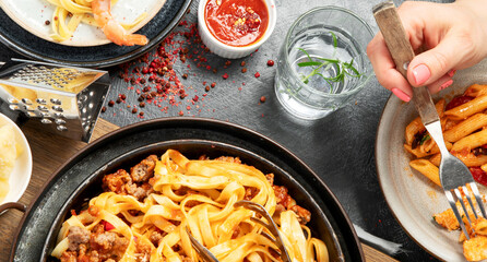 Assortment of Italian pasta with traditional sauces for dinner on dark background. Homemade food concept