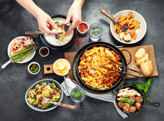 Assortment of Italian pasta with traditional sauces for dinner on dark background. Homemade food concept