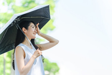 日傘をさして紫外線対策するアジア人女性（笑顔）
