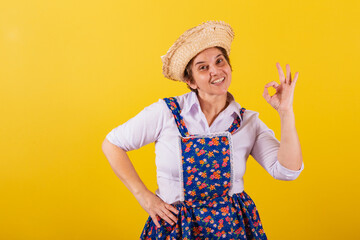 Mature woman dressed in typical Festa Junina clothes. Ok sign with fingers, approval, confirmation,...