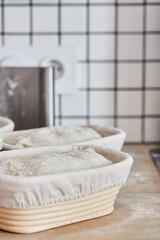 Process of making wheat bread at home. Proofing of the dough in rattan baskets. The concept of healthy homemade food. Vertical photo.